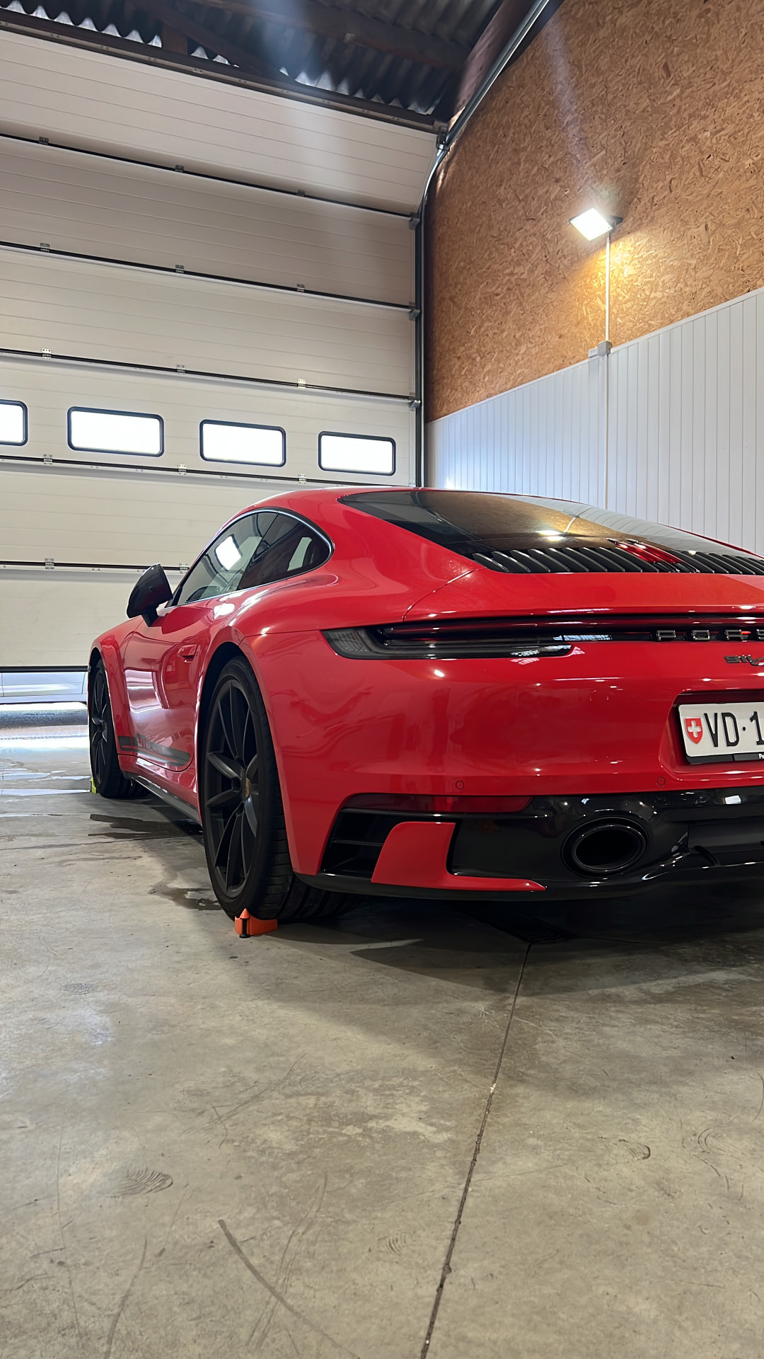 Porsche 911 rouge inspectée sous l'éclairage de l'atelier DCM Morteau